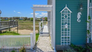Un edificio costero con un porche blanco, una puerta verde y un caballito de mar decorativo.