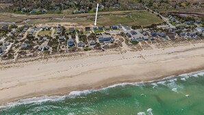 Zona residencial costera con casas a lo largo de la playa y una estructura blanca a lo lejos.