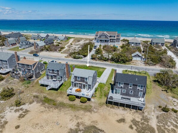 An aerial view of a coastal residential area with houses, a road, and the ocean. - East Sandwich Beach Escape with Marsh Views (East Sandwich)
