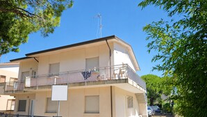 A multi-story residential building with balconies, a visible antenna, and a gated entrance. - Cozy Ground-floor Retreat Near the sea (Lignano Sabbiadoro)