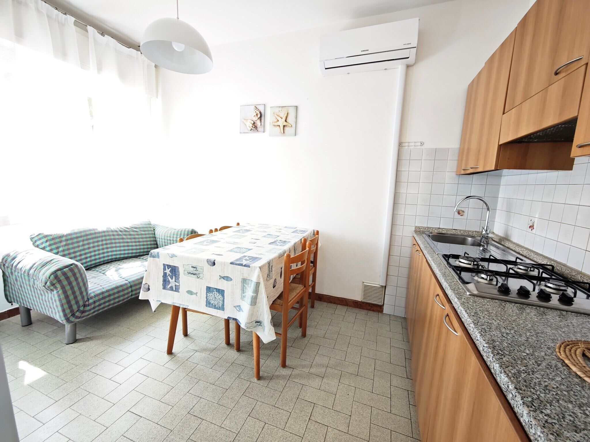 A compact kitchen with a dining table, a sofa, and a gas stove.