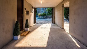 Un couloir avec un paillasson, des plantes en pot et un mur de pierre en arrière-plan.