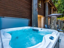 Un jacuzzi con panel de control, zona cubierta y un pilar de piedra.