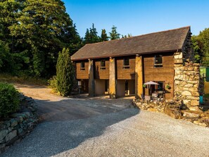 A two-story stone building with a gravel driveway and a wooden deck. - Idris Barn (Dolgellau)