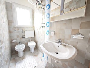 Ein Badezimmer mit Toilette, Bidet, Waschbecken und Dusche.