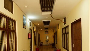 A hallway with patterned floor tiles, a potted plant, and a fire extinguisher. - The Grand Ganga Paying Guest (VARANASI)
