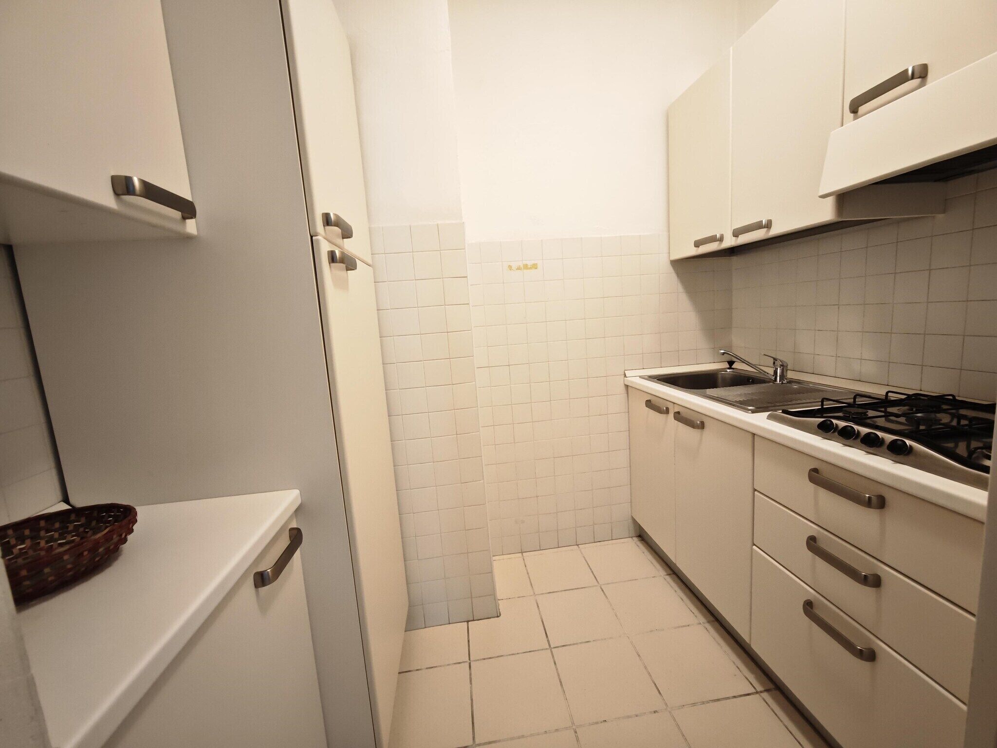 A compact kitchen with white cabinets, a stove, and a sink.