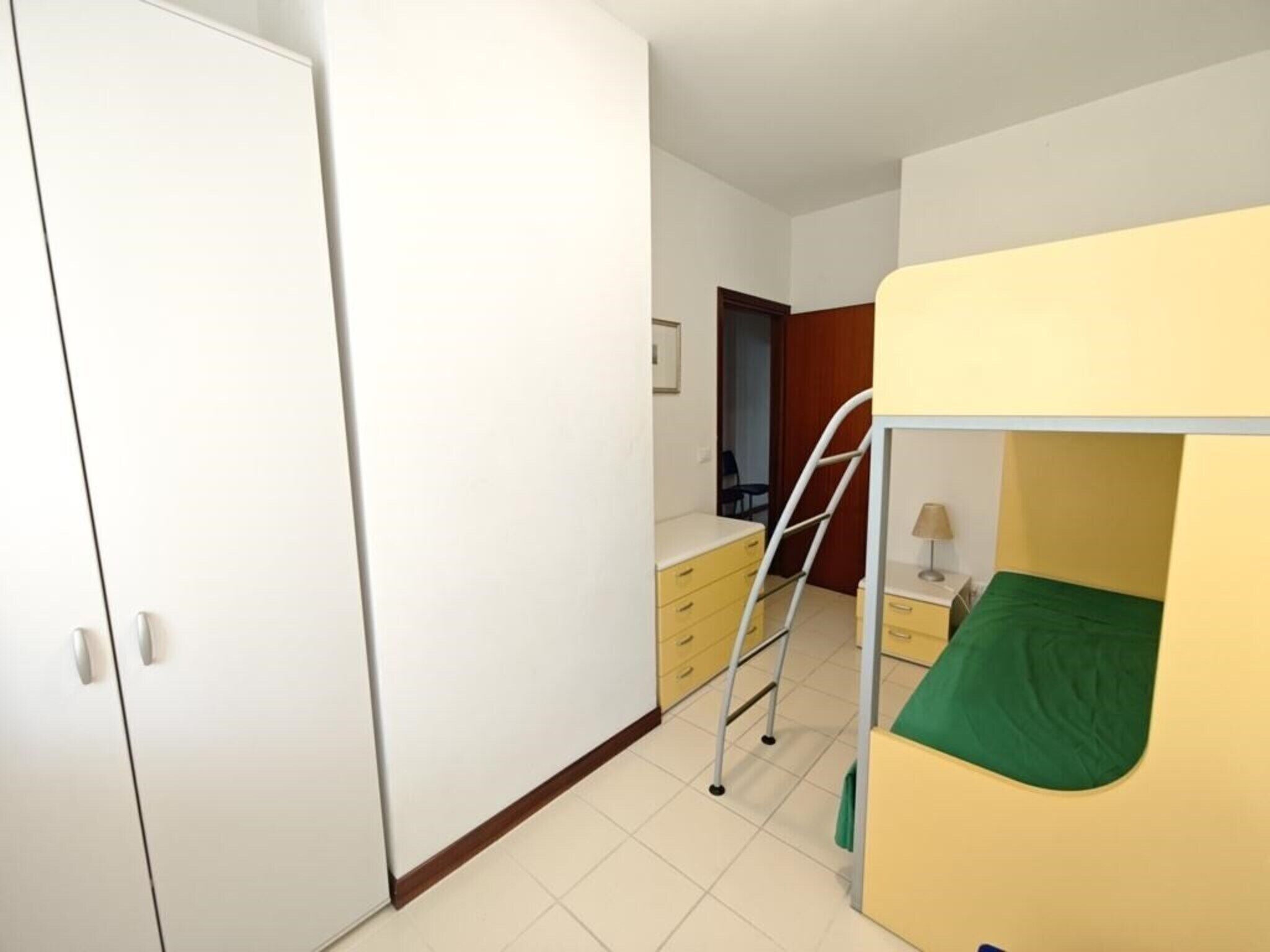 A bedroom with a bunk bed, a wardrobe, a desk, and a chair.