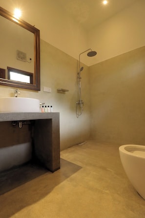 A bathroom with a sink, mirror, shower, and toilet.
