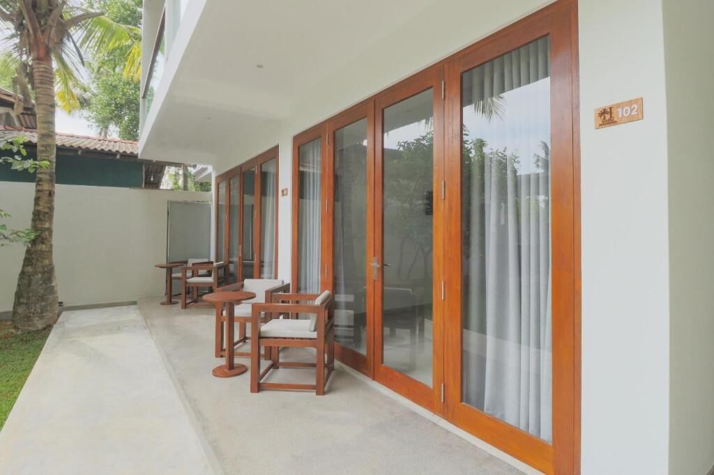 Un área de estar exterior techada con mobiliario de madera y puertas de vidrio.