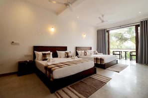 A hotel room with two beds, a balcony, and a ceiling fan.