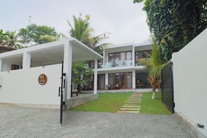 A two-story building with a covered patio, a visible door, and a sign on the wall.
