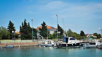 A marina with boats docked, a clear sky, and buildings in the background.