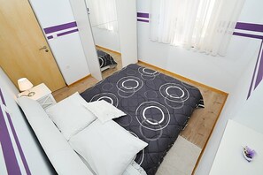 Ein Schlafzimmer mit Bett, Nachttisch, Lampe, Kleiderschrank und Spiegel.