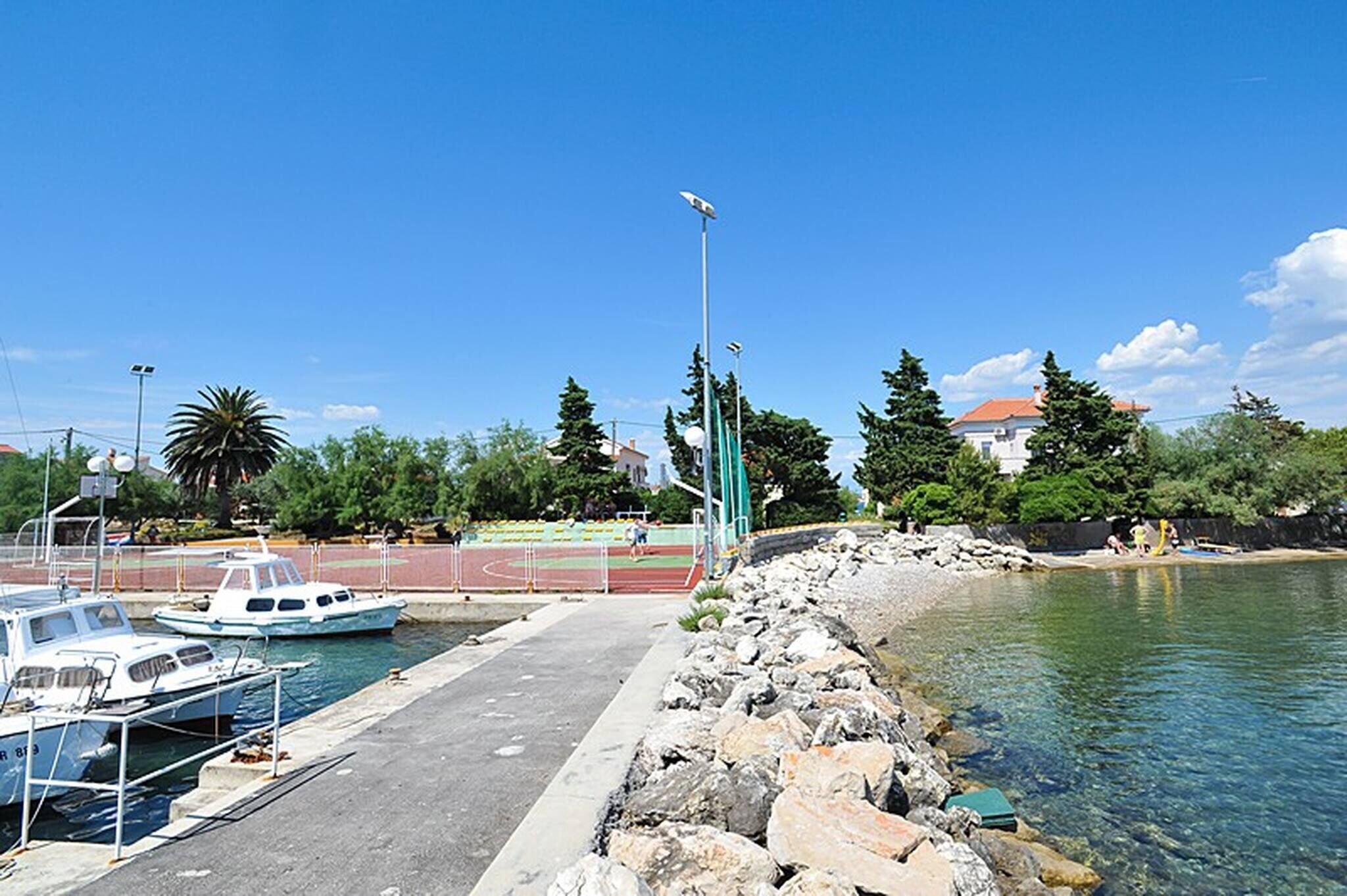 Un port de plaisance avec des bateaux amarrés, une piste d’athlétisme et une côte rocheuse.