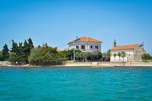A coastal building with a red-tiled roof, a flag, and a clear blue sky. - Amazing Place 4 Peaceful Holiday L (Preko)