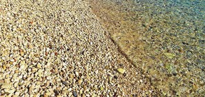 Ein Kiesstrand mit klarem Wasser.