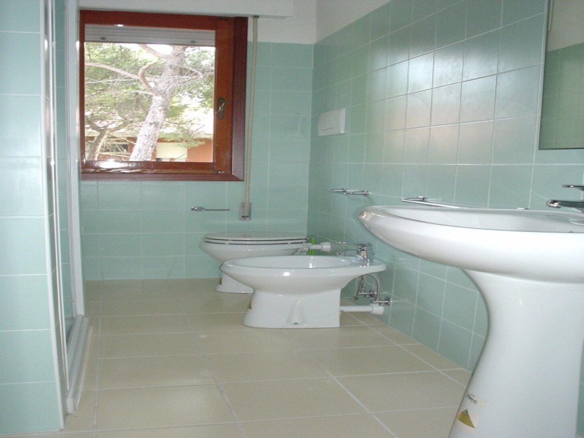 A bathroom with two toilets, a sink, and a window.