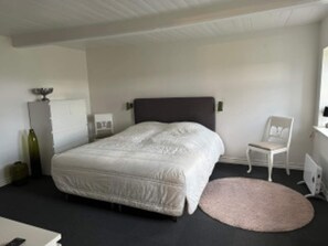 A bedroom with a bed, a chair, a small table, and a radiator. - 4 Star Holiday Home in Sejero (Sejero)