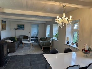Un soggiorno con camino, un'area pranzo con lampadario e vista sull'esterno.