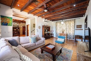 Ein Wohnzimmer mit Holzboden, einer Couch, einem Couchtisch und einem blauen Sessel.