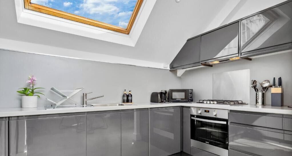 A modern kitchen with a skylight, stainless steel appliances, and a white countertop.