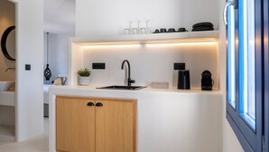Une cuisine moderne dotée d’un évier encastré, de meubles en bois, d’un plan de travail agrémenté de verres et d’une machine à café.