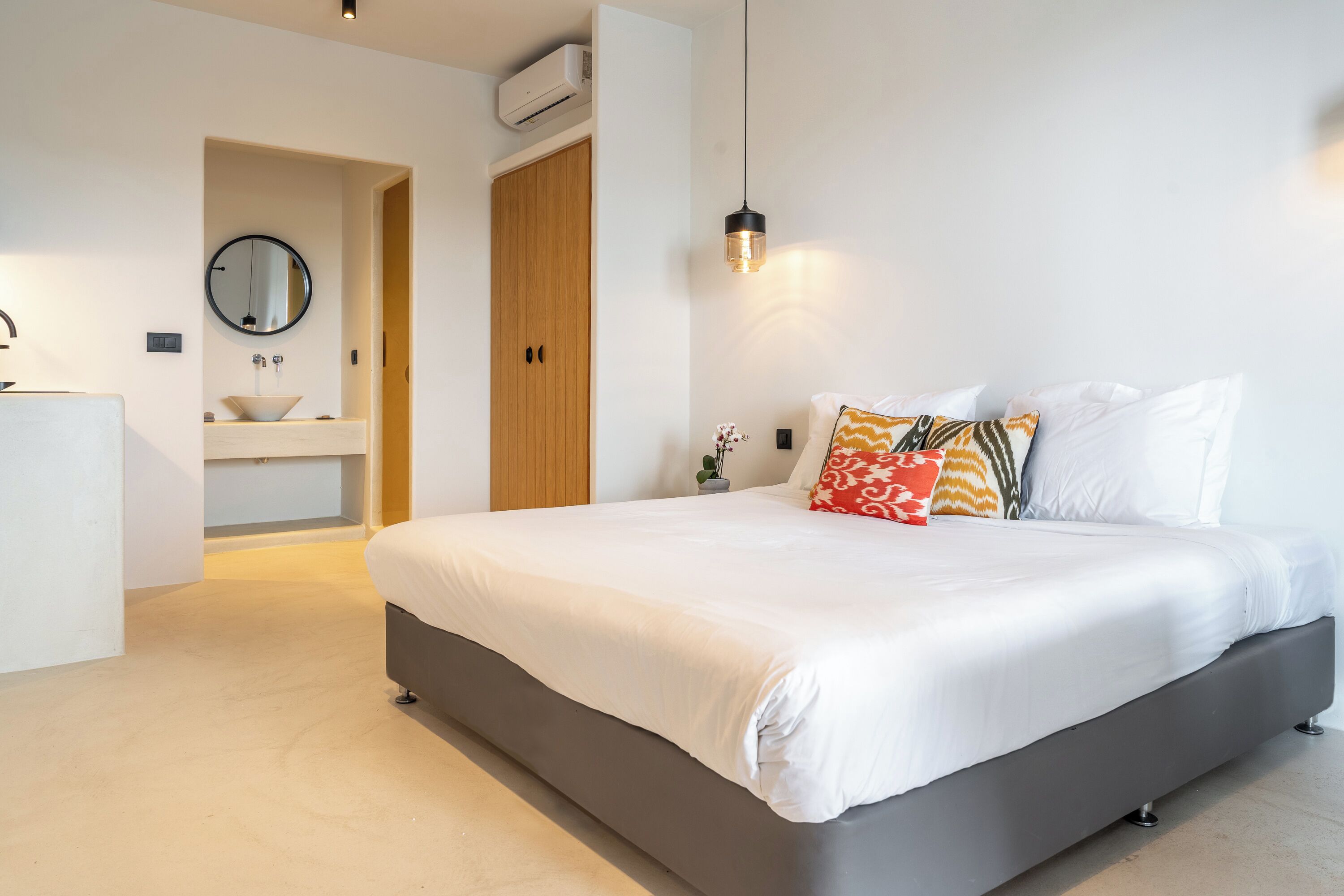 Un dormitorio moderno con una cama grande, una mesita de noche, un espejo y un armario de madera.