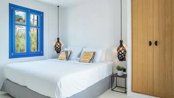 Quarto com cama, janela, guarda-roupa e mesa de cabeceira com uma planta.
