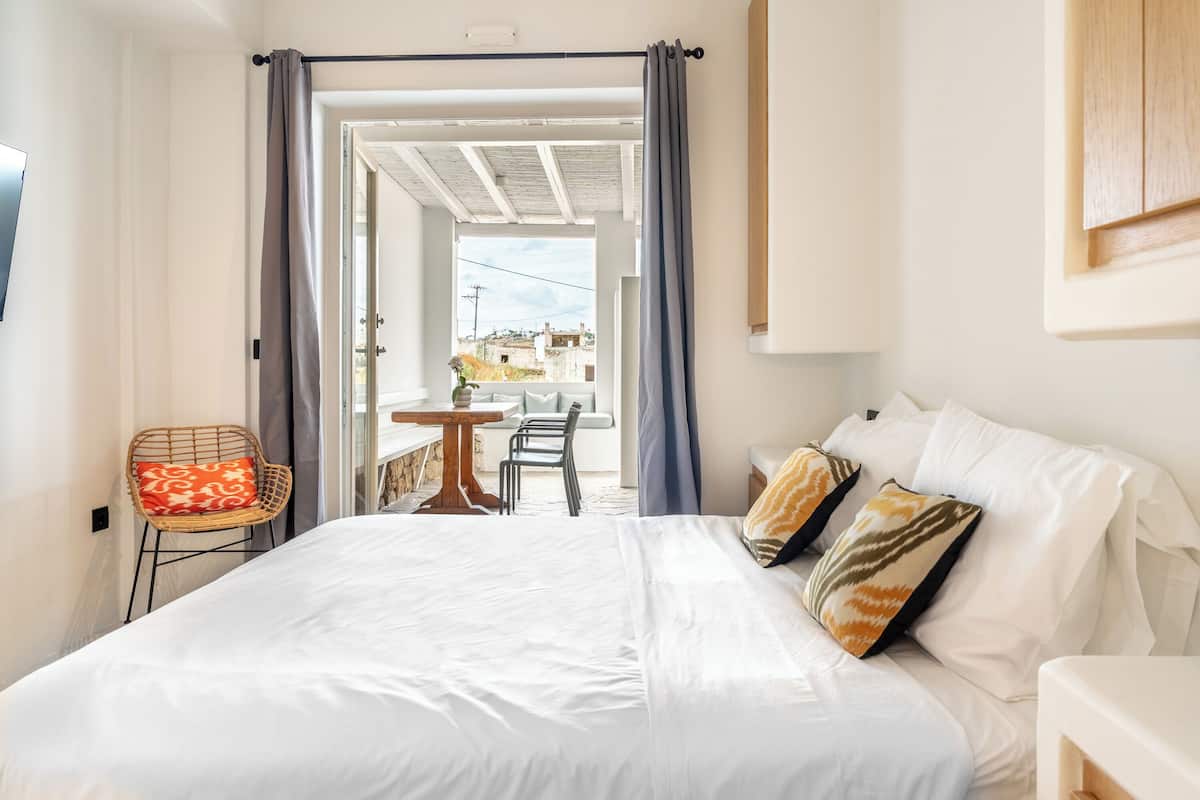 Une chambre à coucher avec un lit, une chaise, une table et une vue sur l’extérieur.
