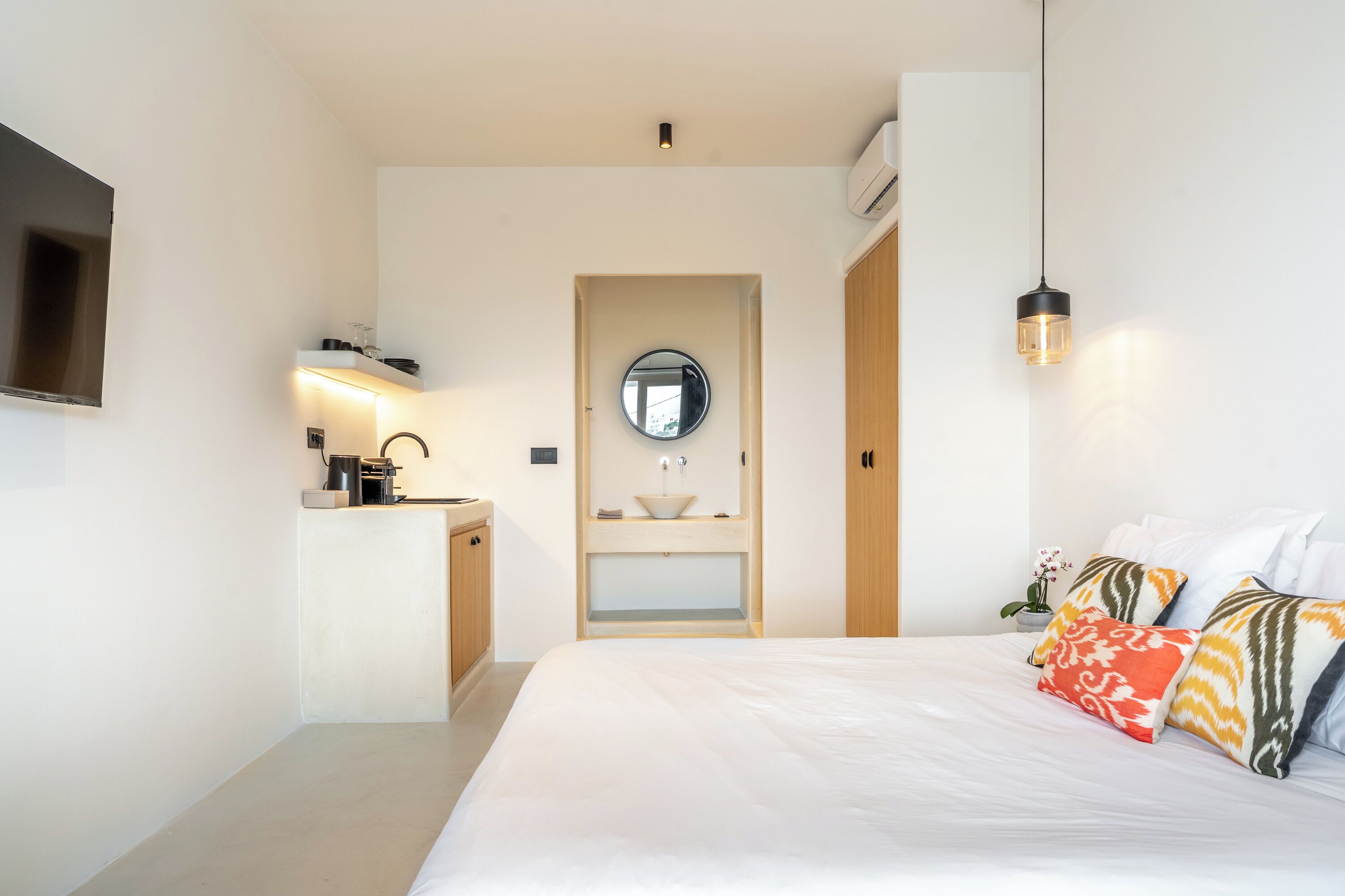 A modern bedroom with a bed, bedside table, and a built-in sink with a mirror.