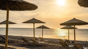 A beach with sun umbrellas and lounge chairs. - Levante Athletic Resort (Rhodes)