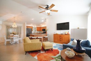 Un soggiorno moderno con ventilatore a soffitto, televisione e zona pranzo con tavolo e sedie.
