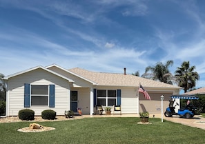 A single-story house with a front porch, a garage, and a lawn. - 2/2 Dog Friendly w/ Golfcart (The Villages)