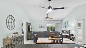 Une cuisine moderne avec un coin repas, un ventilateur de plafond et une grande horloge murale.