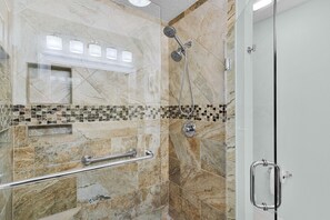 Zona de bany moderna amb porta de vidre, barana i paret revestida de rajoles.