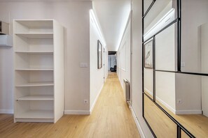 A hallway with white walls, wooden flooring, and a built-in shelving unit on the left. - Travesera de Gracia - bolsa 4h (Barcelona)