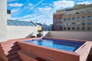 Ein Pool auf dem Dach mit Stufen zum Wasser, umgeben von Gebäuden.