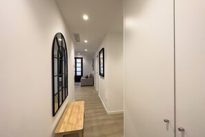 A narrow hallway with a wooden bench, a large mirror, and a door at the end. - 2 Bedroom apartment - Two Bedroom Apartment, Sleeps 4 (Barcelona)