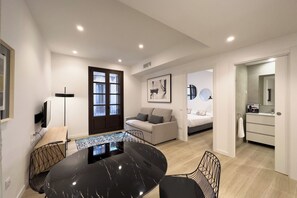 A modern living room with a dining table, sofa, and a large window. - 2 Bedroom apartment - Two Bedroom Apartment, Sleeps 4 (Barcelona)