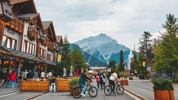 Une ville de montagne avec des bâtiments en bois, une rue animée et une montagne en arrière-plan.