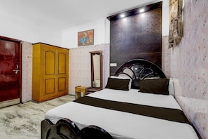 A bedroom with a bed, wooden wardrobe, a mirror, and a wall-mounted artwork. - Hotel O Madipakkam Lakeview Chennai (Chennai)