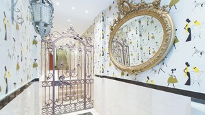 A hallway with a decorative gate, a large ornate mirror, and patterned wallpaper. - Ample Bolsa estándar tipo 1 (Barcelona)