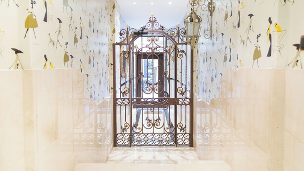 A hallway with a decorative iron gate, patterned wallpaper, and a marble floor. - Ample Bolsa estándar tipo 1 (Barcelona)