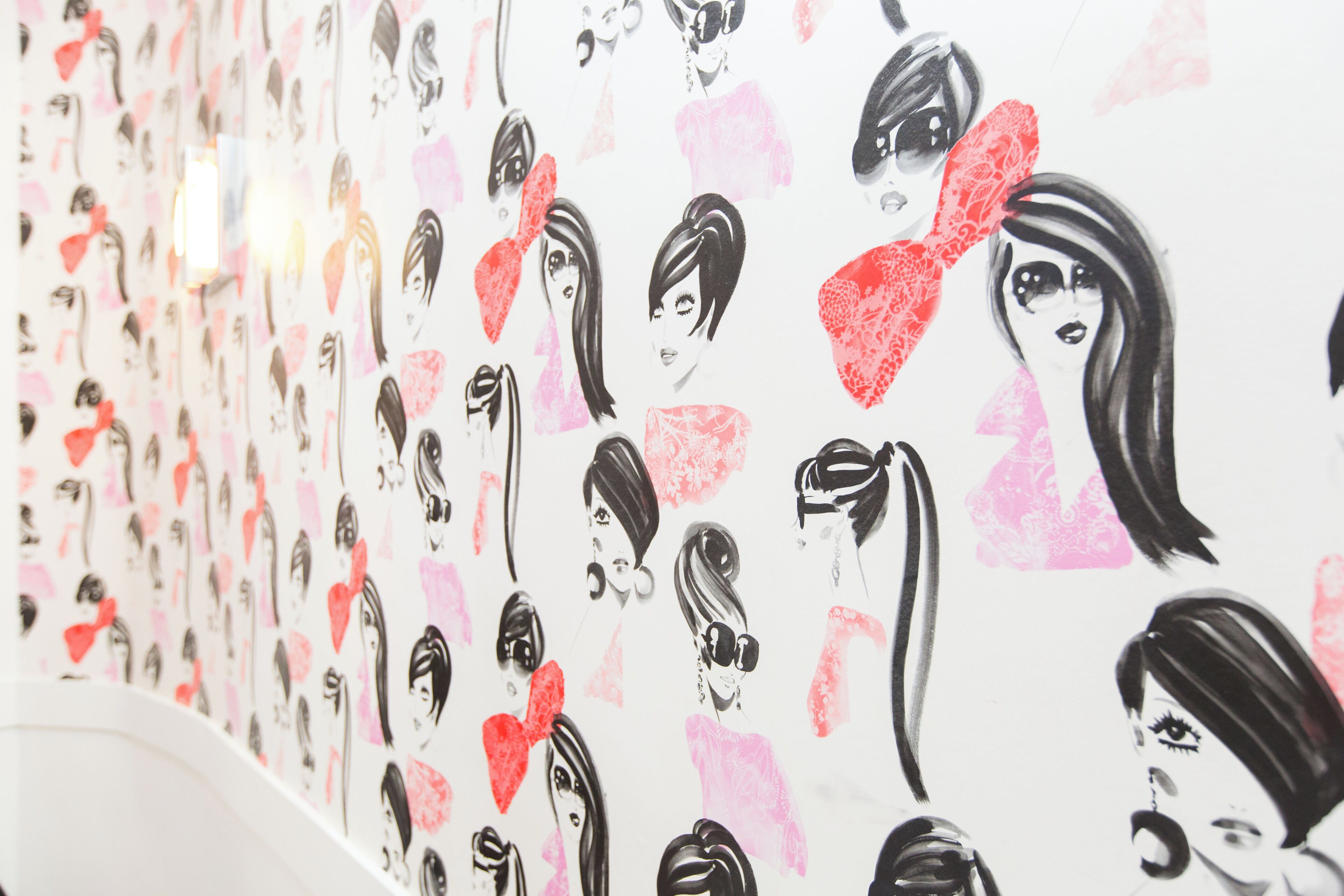 Un mur orné de nombreuses illustrations représentant des femmes coiffées et vêtues de différentes manières.
