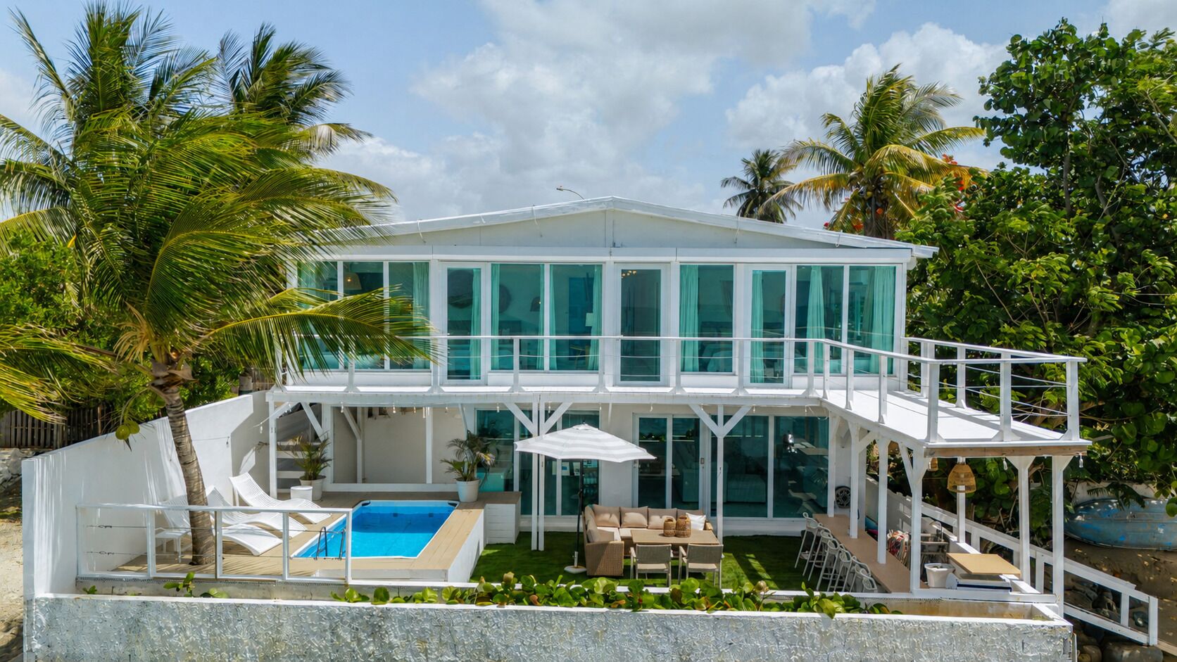 Une maison moderne dotée d’une piscine, d’un espace salon extérieur et d’un patio couvert.