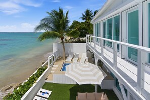 Ein Balkon mit Pool, Liegestühlen und Meerblick.