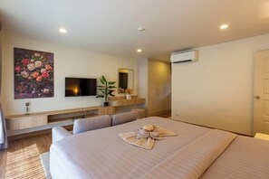 Ein Hotelzimmer mit Bett, Fernseher, Pflanze und einem Bild an der Wand.