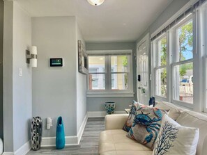 A hallway with a beige sofa, a blue vase, and a wall-mounted thermostat.