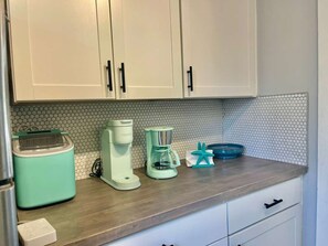 A kitchen with white cabinets, a toaster, a coffee maker, and a blue dish rack.